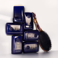 Several Oribe Supershine Smoothing Wax Sticks with a hairbrush