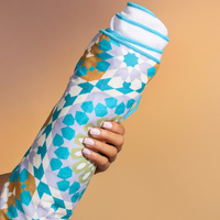 Hand holding the rolled Bounce Curl Micro-fiber Beach Towel, showing its geometric print