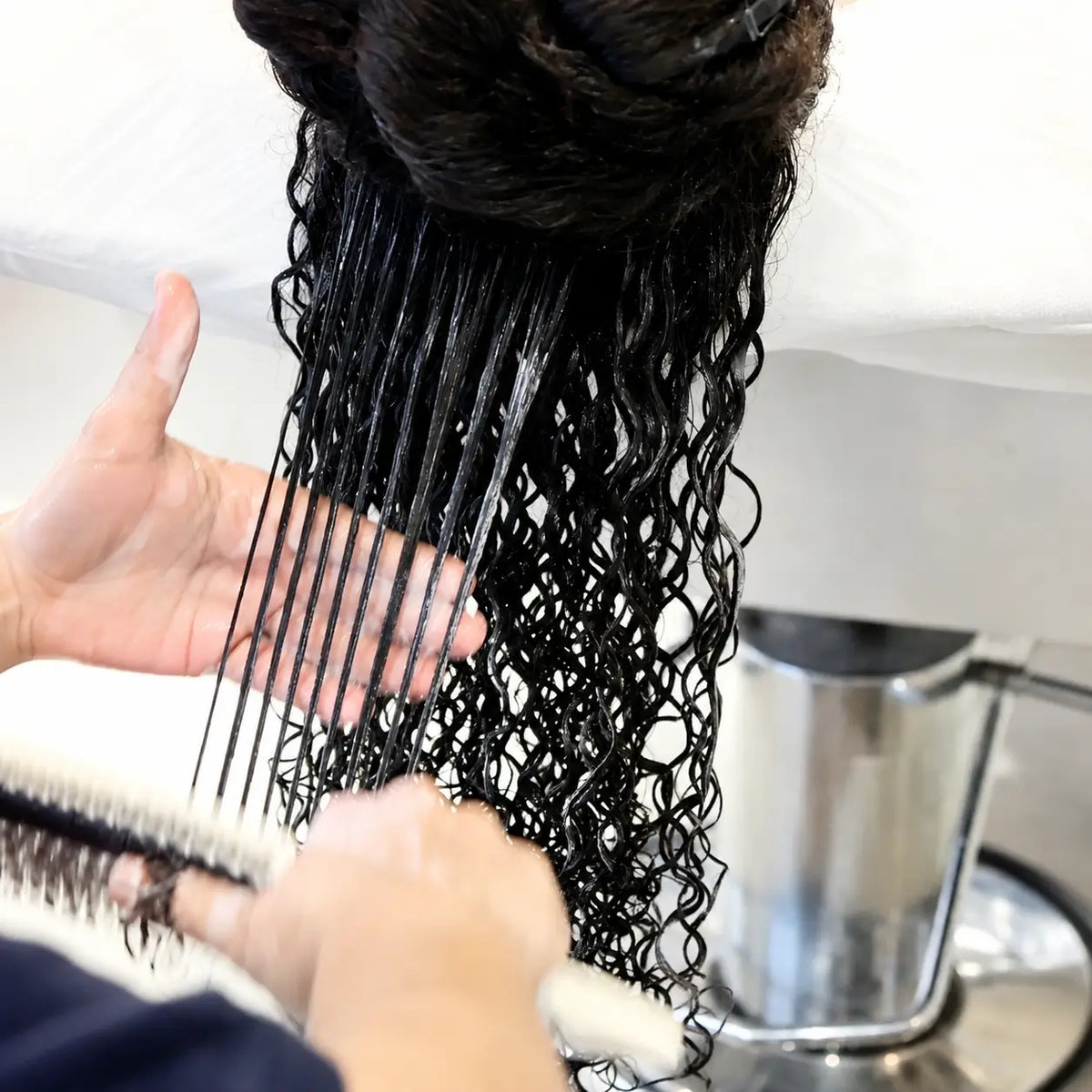 Stylist brushing through wet curly hair