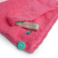 Close-up of the Cataleya label and button on the fuchsia turban hair towel
