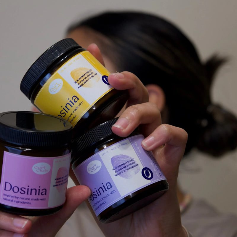 Model holding three jars of Dosinia Hair Mask