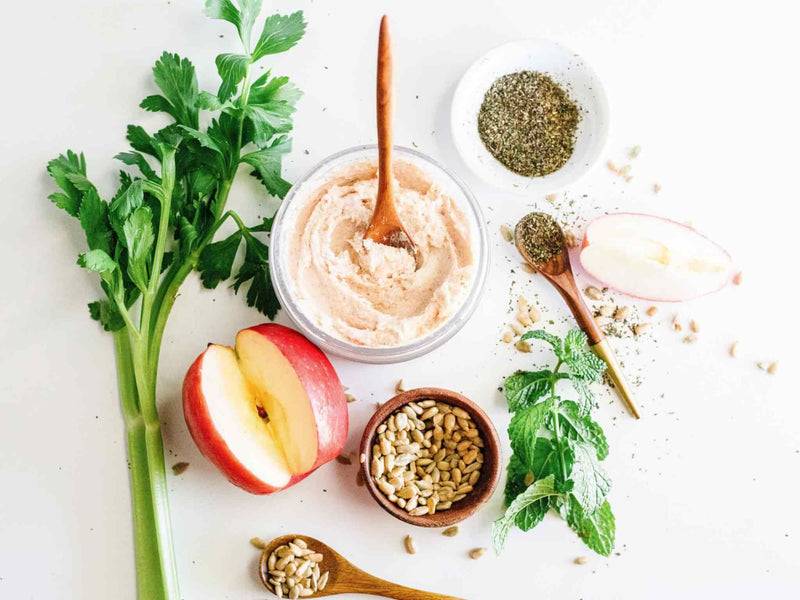 Flat lay of Innersense True Enlightenment Scalp Scrub with apple, celery, herbs and seeds